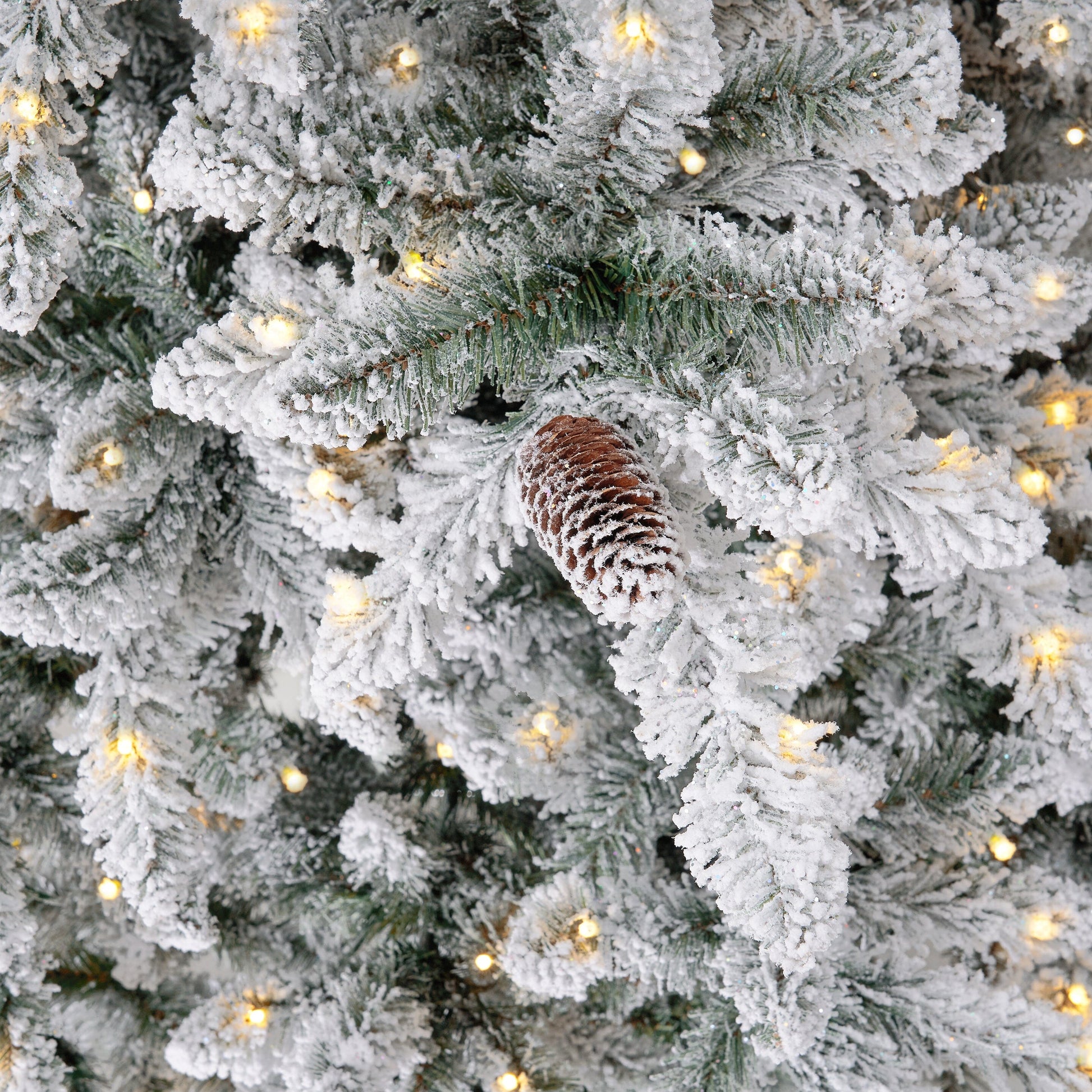 The 10’ Flocked Livingston Fir Artificial Christmas Tree in a living room setting, illuminating the space with 750 LED lights.